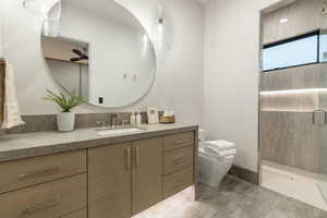 Bathroom featuring tile patterned flooring, toilet, walk in shower, ceiling fan, and vanity