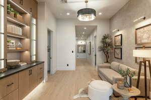 Hall featuring an inviting chandelier and light hardwood / wood-style flooring