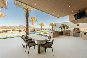 View of patio / terrace with a mountain view, a bar, an outdoor kitchen, area for grilling, and a fenced in pool