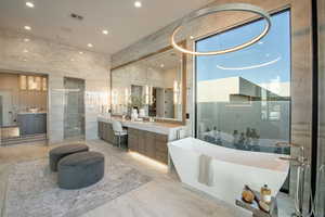 Bathroom featuring tile walls, a tub to relax in, and vanity