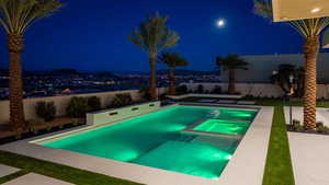 Pool at night featuring an in ground hot tub