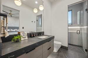 Bathroom with toilet, vanity, an enclosed shower, and ceiling fan