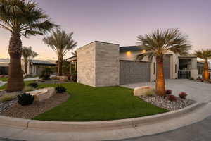 View of front of home with a garage and a yard