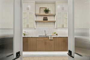 Bar featuring white cabinets, sink, and backsplash