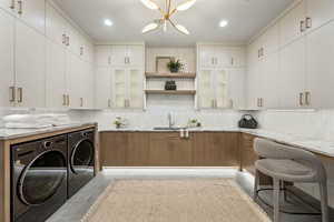 Kitchen with white cabinetry, sink, separate washer and dryer, and light stone counters