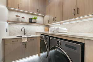 Laundry room with washing machine and dryer, sink, and cabinets