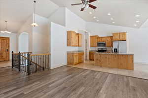 Kitchen with stainless steel appliances, light stone counters, pendant lighting, sink, and a kitchen island with sink