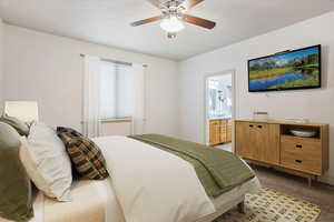 Bedroom featuring ensuite bathroom, a ceiling fan, and light colored carpet