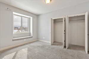 Unfurnished bedroom featuring multiple closets, a textured ceiling, and light colored carpet