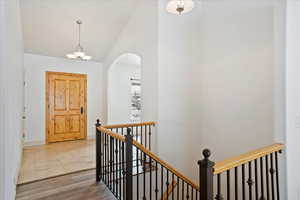 Corridor with hardwood / wood-style flooring, a chandelier, and lofted ceiling