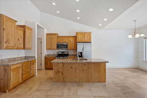 Kitchen featuring a center island with sink, hanging light fixtures, stainless steel appliances, light stone countertops, and sink