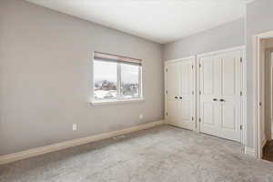 Unfurnished bedroom featuring multiple closets and light colored carpet