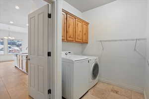 Washroom featuring cabinets, washing machine and clothes dryer, an inviting chandelier, sink, and a textured ceiling