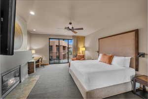 Carpeted bedroom featuring ceiling fan, a tile fireplace, and access to exterior