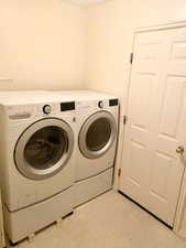 Laundry area with laundry area, light floors, and separate washer and dryer