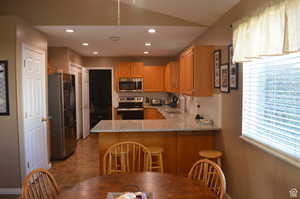 Kitchen featuring appliances with stainless steel finishes, tasteful backsplash, light stone countertops, sink, and kitchen peninsula