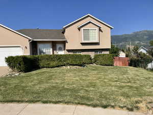 View of front of house featuring a garage, a mountain view, and a front yard