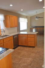 Kitchen featuring tasteful backsplash, dishwasher, lofted ceiling, sink, and kitchen peninsula