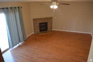 Unfurnished living room with a fireplace, ceiling fan, and hardwood / wood-style floors