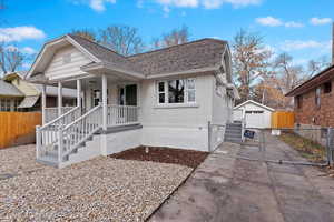 Bungalow featuring covered porch, a garage, and an outdoor structure