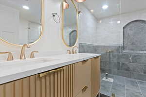 Bathroom featuring a tile shower and vanity