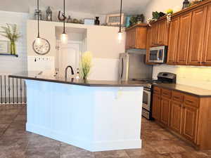 Kitchen featuring hanging light fixtures, a breakfast bar area, stainless steel appliances, vaulted ceiling, and sink