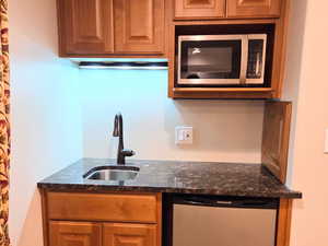 Wet Bar featuring dark stone countertops, fridge, and sink