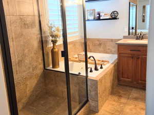 Bathroom featuring separate shower and tub, vanity, and a healthy amount of sunlight