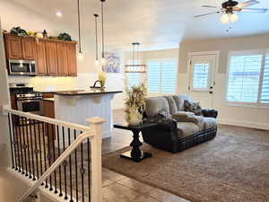 Kitchen with appliances with stainless steel finishes, hanging light fixtures, a breakfast bar area, dark carpet, and ceiling fan