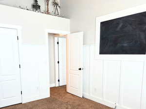 Unfurnished bedroom featuring ceiling fan, dark colored carpet, and lofted ceiling