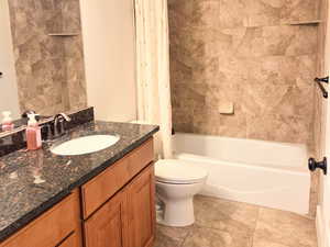 Full bathroom with shower / tub combo with curtain, toilet, vanity, and a textured ceiling