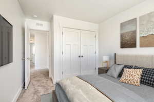 Bedroom with a closet, a textured ceiling, and light colored carpet