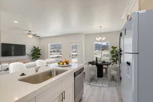 Kitchen with fridge with ice dispenser, hanging light fixtures, dishwasher, sink, and white cabinetry