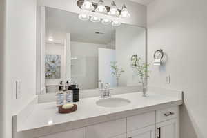 Bathroom featuring vanity, toilet, and a shower