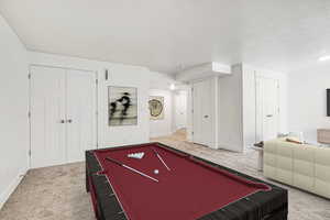 Game room featuring carpet floors, billiards, and a textured ceiling