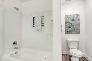 Bathroom featuring toilet, shower / bathing tub combination, and wood-type flooring