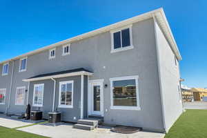 Rear view of house featuring a yard, central air condition unit, and a patio