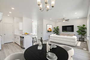 Living room featuring ceiling fan with notable chandelier, light wood-type flooring, and sink