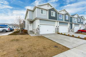 Townhome / multi-family property with driveway, a front lawn, an attached garage, and a residential view