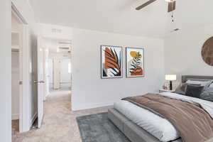 Carpeted bedroom featuring vaulted ceiling and ceiling fan