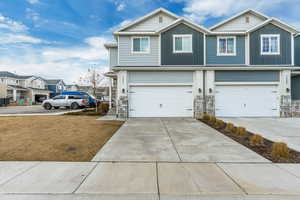 View of front of property with a garage, concrete driveway, board and batten siding, and a residential view