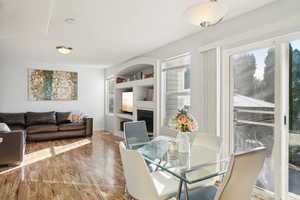 Dining area with built in shelves and wood-type flooring