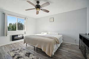 Bedroom with dark hardwood / wood-style flooring, ceiling fan, and a textured ceiling