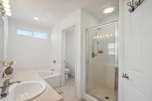 Full bathroom featuring tile patterned floors, toilet, vanity, and shower with separate bathtub