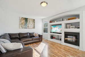 Living room with wood-type flooring and built in shelves