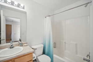 Full bathroom with shower / tub combo with curtain, toilet, and vanity