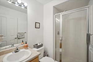 Bathroom featuring vanity, toilet, and a shower with shower door