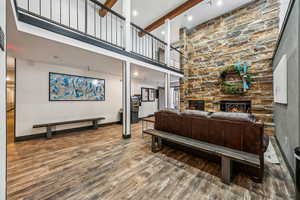 Living room featuring a fireplace, beamed ceiling, wood-type flooring, and a towering ceiling