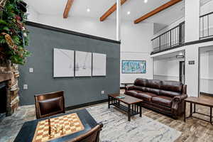 Living room with a fireplace, beamed ceiling, a high ceiling, and hardwood / wood-style floors