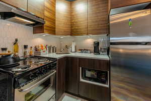 Kitchen with sink, appliances with stainless steel finishes, dark brown cabinets, and decorative backsplash